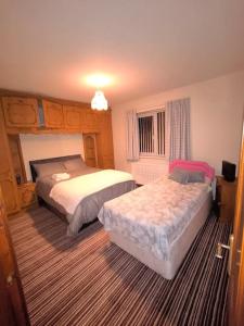 奥马Cosy 3 Bed Retreat in Omagh的一间卧室设有两张床和窗户。