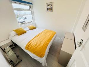 Brading2 Bedroom Chalet SB84, Sandown Bay, Dog Friendly的一间卧室配有一张带黄色床单的床和一扇窗户。