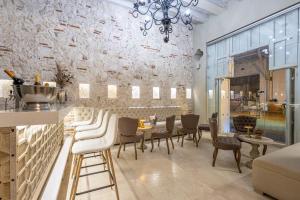 卡塔赫纳Hotel Casa del Gobernador的一间设有白色椅子和石墙的用餐室