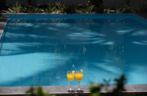 乌纳瓦图纳Villa Windfall Unawatuna的两杯橙汁坐在游泳池旁