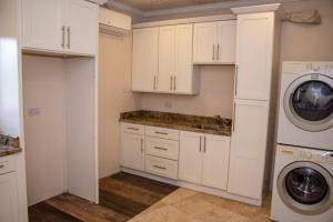 金斯敦La Cresta的厨房配有白色橱柜、洗衣机和烘干机