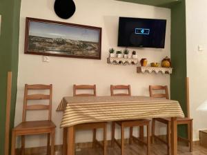 蒙托罗Una casita al completo en Montoro的餐桌、椅子和墙上的电视