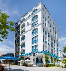 岘港Santori Hotel And Spa的白色的大建筑,设有蓝色的阳台