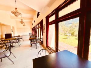 马拉里Sagar Heritage Resort, Manali的用餐室配有桌椅和大窗户