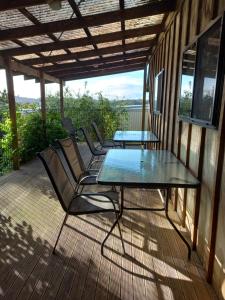 OpuaPinelodge的露台设有玻璃桌子和椅子,甲板上设有