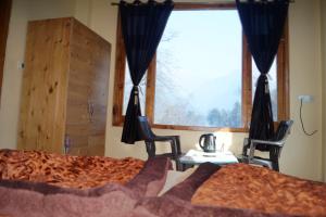 卡索尔Apple Garden Katagla Kasol的一间卧室配有一张床、两把椅子和一个窗户