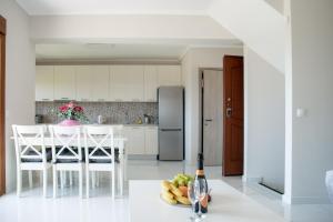 波利克罗诺Vacation house with a panoramic sea view and forest的白色的厨房,配有带水果和一瓶葡萄酒的桌子