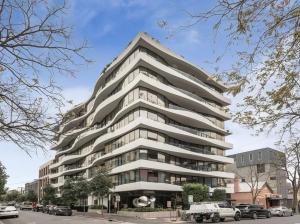 墨尔本Apartment in South Melbourne的一座高大的白色建筑,前面有汽车停放