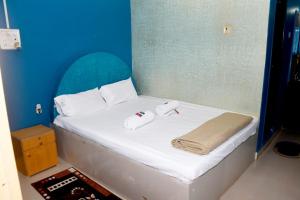 马尔万KonkanParadise,Hotel Malvan Beach的一张白色的床,上面有两条毛巾,还有蓝色的墙壁