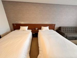 茅野多佳尼西酒店 的带沙发的客房内的两张床
