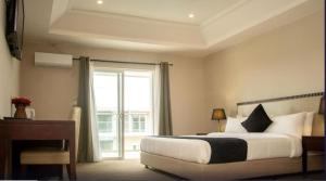 HarbelTIME Royal Ambassador Hotel的一间卧室配有一张床、一张书桌和一个窗户。