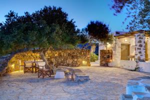 帕罗斯岛ELEONAS Paros estate - villas with partially private pools & professional tennis court的一个带椅子的庭院和夜间石墙