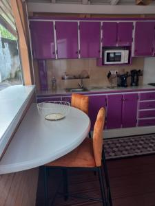 Rivière-PiloteJoli appartement的厨房配有紫色橱柜和白色的桌椅
