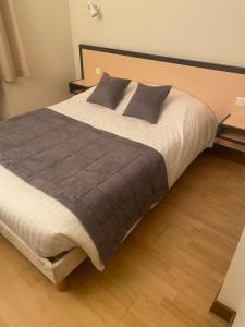 Joncyhotel du commerce的卧室内的一张大床,铺有木地板