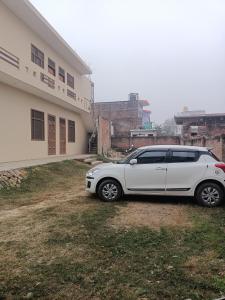 AyodhyaARJUN PAYING GUEST HOUSE的停在大楼前的白色汽车