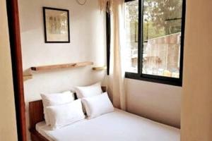 AndjamenBungalow Ramena beach Antsiranana的卧室配有带白色枕头的床和窗户。