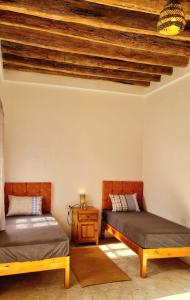 托泽尔Maison d'hôtes "Dar Khalifa"的客房设有两张床和木制天花板。