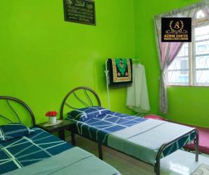 马六甲ASTANA SHAFIIS的绿色的客房设有两张床和窗户。