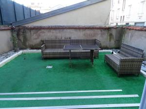 南希Appartement Artem neuf et terrasse的天井设有2张长椅和1张桌子,位于草地上