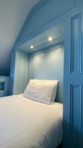 韦茅斯费尔赫维酒店的蓝色客房内的一张带白色枕头的床