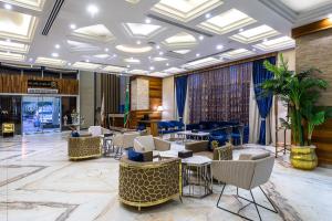 利雅德Crown Rose AlSahafa Hotel的大堂设有桌椅和钢琴