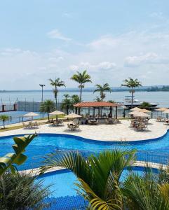 巴西利亚Flat beira lago no centro de BSB的一个带桌子和遮阳伞的大型游泳池,并享有海景。