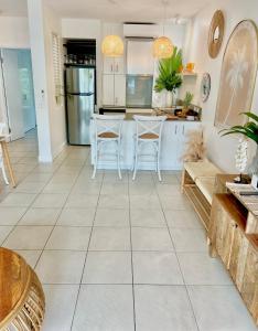 棕榈湾Peppers Beach Club Penthouse的厨房铺有白色瓷砖地板,配有桌椅。