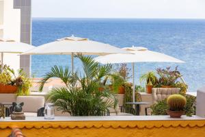 圣克鲁斯-德拉帕尔马圣特尔莫酒店的一个带桌子和遮阳伞的庭院和大海