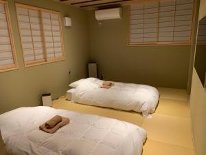东京伊东日式旅馆的配有窗户和白色床单的客房内的两张床