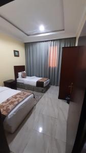 达瓦迪米شقق مساكن السمو المخدومة的酒店客房设有两张床和窗户。