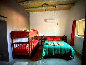蒂诺加斯塔El Cortijo Tinogasta的一间卧室配有两张双层床,铺有红色和绿色的床单。