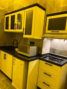 利雅德استديو فاخر حي حطين بجوار البوليفارد的厨房配有黄色橱柜和微波炉