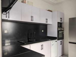洛美Dapi Home Residence的厨房配有白色橱柜和黑色台面
