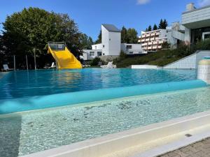 圣恩吉玛Hecht Ferienvermietung - Studio Buchfink mit Sauna und Schwimmbad的游泳池中的黄色水滑梯