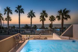 赫索尼索斯Royal & Imperial Belvedere Resort的棕榈树酒店游泳池享有海景
