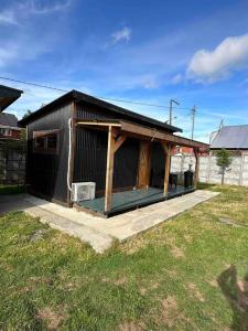 奥克泰港Espectacular Tiny House,terraza,Aire acondicionado的一座黑色的小建筑,在院子里设有门廊