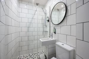 爱丁堡Queen Charlotte Guesthouse的白色瓷砖浴室设有水槽和镜子