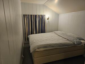 特罗姆瑟Tønsvik enebolig的一张小床,位于带窗帘的房间