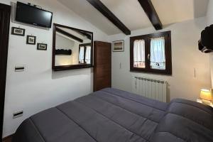 桑格罗堡[FREE PARKING] La Bianca Neve Cottage的卧室配有一张床,墙上配有电视。