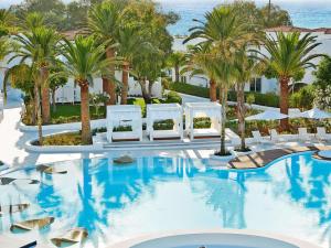 阿德里安诺斯坎波斯卡拉梅尔雷科泰尔精品度假村的酒店游泳池设有白色椅子和棕榈树
