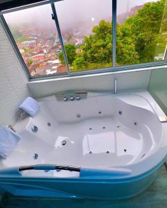 AguadasHotel Casa Blanca的带浴缸的浴室和大窗户