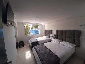 AguadasHotel Casa Blanca的酒店客房设有两张床和窗户。