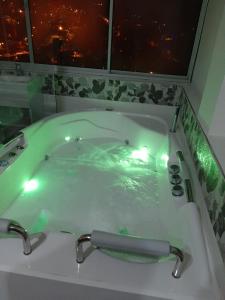 AguadasHotel Casa Blanca的以及配有绿水和灯光的浴缸。