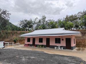 BalingHomestay Teratak D`kemangi with Private Pool的粉红色的建筑,前面设有野餐桌