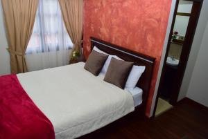 昆卡Hostería La Travesía Campiña的卧室配有白色床和棕色枕头