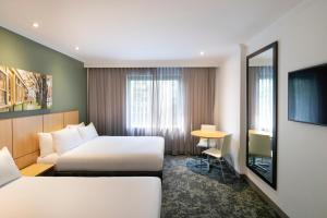 墨尔本Mercure Melbourne Southbank的酒店客房设有两张床和一张桌子。