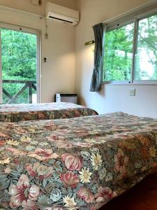 南阿苏村Garden Villa Minamiaso的带2扇窗户的客房内的2张床