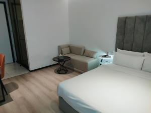 上海上海盎格酒店(新国际博览中心龙阳路地铁站店)的一间卧室配有一张床、一把椅子和一张沙发