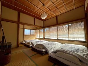 镰仓市古民家の宿 鎌倉楽庵 - Kamakura Rakuan -的带2扇窗户的客房内的2张床