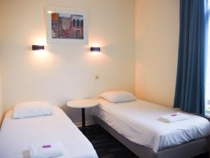 阿姆斯特丹尤菲米娅老城区运河区廉价酒店的客房设有两张床、一张桌子和一扇窗户。